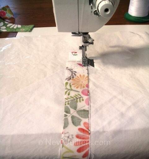 Photo of fabric strip being sewn onto string quilt block