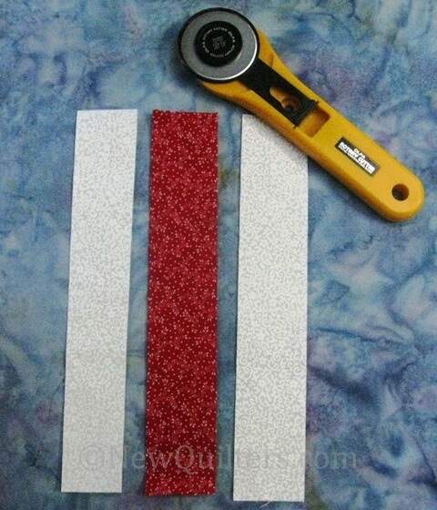 Photo of three fabric strips with rotary cutter