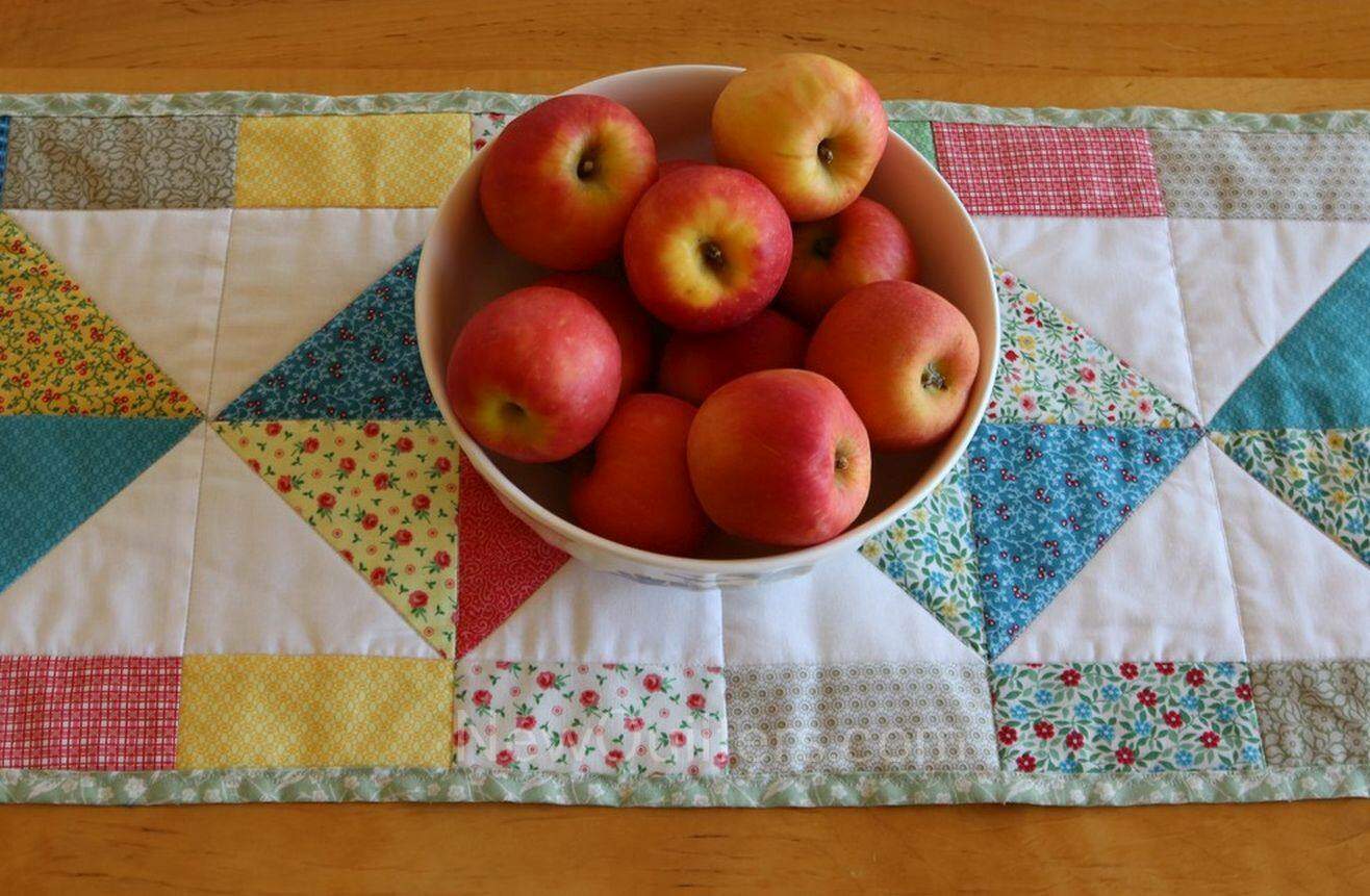 Quilters, use 5" charm squares to make this cheerful little 12" x 41" self-bound table runner. Tutorial from NewQuilters.com #quiltingforbeginners, #tablerunner
